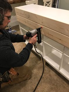 a man using a power drill to attach a piece of wood on top of a shelf