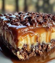 a piece of cake with chocolate and caramel toppings on a white plate in front of a window