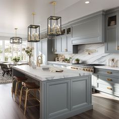 a large kitchen with gray cabinets and marble counter tops, gold accents on the island