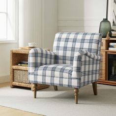 a blue and white plaid chair sitting in front of a window next to a basket