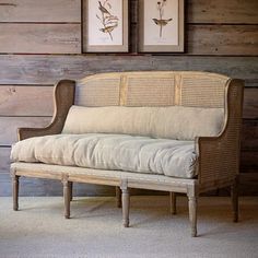 a couch sitting next to a wooden wall with two framed pictures on it's side