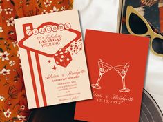 two wedding cards on top of a table next to sunglasses and a pair of glasses