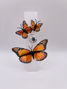 These hair clips"Monarch Disco Duo," combine the whimsical beauty of monarch butterflies with the playful sparkle of a mini disco ball.  The set features a larger butterfly clip, and a clip with two smaller butterflies perched around a shiny mirrored disco ball accent.  The combination of nature-inspired elegance and retro glam creates a unique, eye-catching accessory, perfect for adding a touch of boldness and fun to any look. These make FANTASTIC Halloween costume accessories! So easy to wear, adorable and fun to wear as you move so will your butterflies wings!🦋 Largest Butterfly, Halloween Costume Accessories, Butterfly Clips, Costume Halloween, Monarch Butterfly, Disco Ball, Butterfly Wings, Barrettes, Costume Accessories