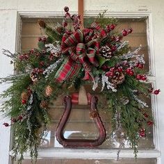 a christmas wreath hanging on the side of a door with pine cones and evergreens