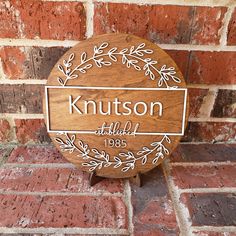 a wooden sign that says knutson with leaves around it on a brick wall