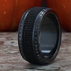 a ring with black diamonds is sitting on a table next to some pumpkins and an orange