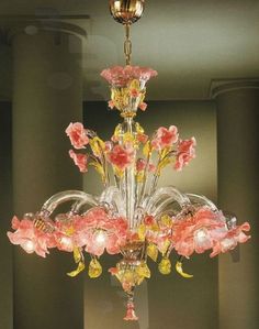 a chandelier with pink flowers hanging from it's centerpiece in a room