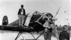 two people standing next to an old airplane