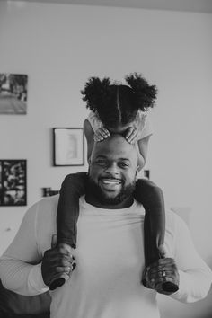 a black and white photo of a man holding a child on his shoulders