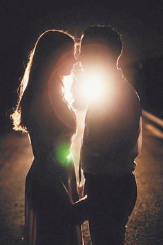 a man and woman standing next to each other in front of a street light at night