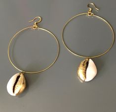 The cowrie shell once utilized as exchange currency, is revered as a symbol of fertility, goddess protection, wealth, and powerful in its connection to the strength of the ocean.  These shells have been hand leafed with gold tone leaf, base metal hoops and ear wires.  Few pairs available as these are custom made to order. Spiritual Gold Shell-shaped Jewelry, Spiritual Gold Shell Jewelry, Handmade Gold Hoop Earrings For Beach, Gold Pierced Hoop Earrings For Beach, Gold Small Hoop Jewelry For The Beach, Gold Teardrop Jewelry For Beach, Gold Teardrop Jewelry For The Beach, Gold Shell-shaped Hoop Earrings For Beach, Gold Metal Hoop Earrings For Beach