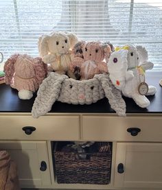 several stuffed animals sitting on top of a dresser next to a window with blinds in the background