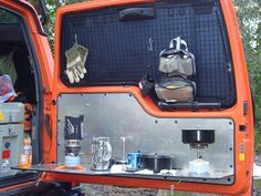 an orange truck with its back door open and camping gear in the cargo compartment,