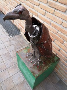 a statue of a bird with gears in its beak on top of a green box