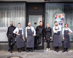 a group of men and women standing in front of a building with aprons on