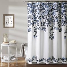 a shower curtain with blue flowers on it in a white and gray bathroom setting next to a bathtub