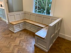 a corner bench in the middle of a room with wood flooring and white walls