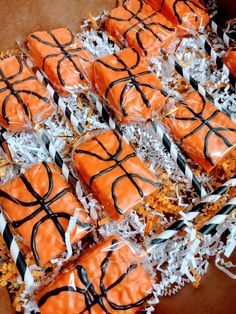 orange and black decorated cookies in a box with white shredded paper on the bottom,