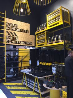 people are standing in front of the work progress under construction sign and yellow ladders