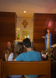 two people are sitting in a church pews with flowers on the side and a statue of jesus behind them