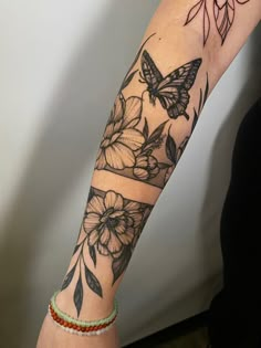 a woman's arm with a butterfly and flowers tattoo on the left side of her arm