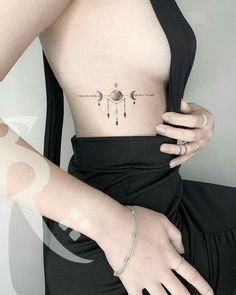 a woman wearing a black dress has a tattoo on her stomach and is holding onto the arm