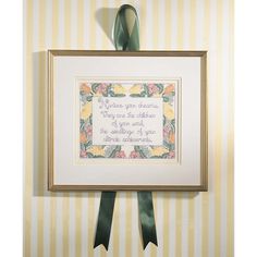 a cross - stitch pattern hanging on the wall with ribbon