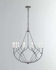 an iron chandelier with eight candles hanging from the center, on a gray background