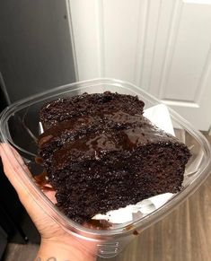 a hand holding a plastic container filled with cake