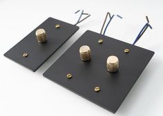 two black square plates with gold knobs and screws on them, one in the middle