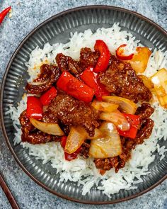 a plate with rice, meat and vegetables on it next to some chopsticks