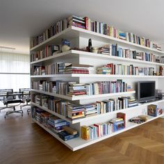 a bookshelf filled with lots of books next to a tv on top of a hard wood floor