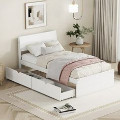 a white bed with two drawers underneath it in a room next to a rug and table