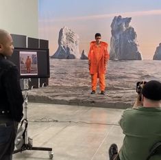 a man in an orange jumpsuit is filming another man