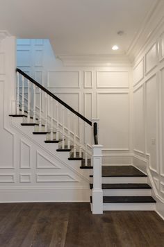 an empty room with white walls and black stairs