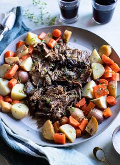 a white plate topped with meat, potatoes and carrots