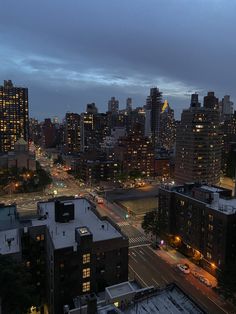 the city skyline is lit up at night, with buildings in the foreground and street lights on