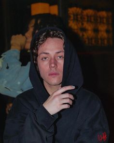 a man in a black hoodie holding his finger up