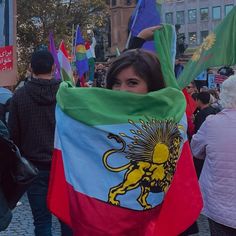 a woman is holding a flag in the middle of a street with other people walking around