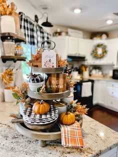 three tiered trays filled with pumpkins on top of a kitchen counter