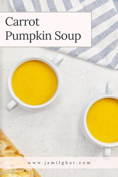 two cups of carrot pumpkin soup next to a loaf of bread