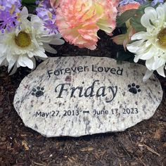 a memorial stone with the words, forever loved friday written on it in front of flowers