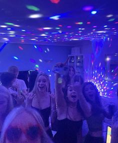 a group of people standing around each other in a room with lights and confetti on the ceiling