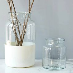 a vase with branches in it next to a glass jar