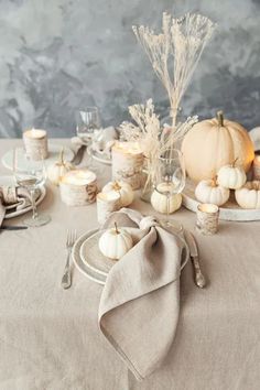 the table is set with white pumpkins and other items for thanksgiving or fall dinner