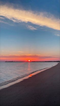 the sun is setting over the water at the beach in front of an ocean shore