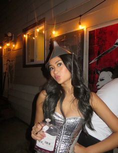 a woman wearing a silver dress and a party hat holding a bottle in her hand