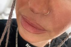 a close up of a person with a nose ring and braids in her hair