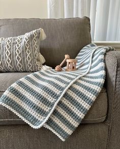 a crocheted blanket sitting on top of a couch next to a wooden toy horse