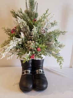 a pair of black boots with flowers and greenery in them